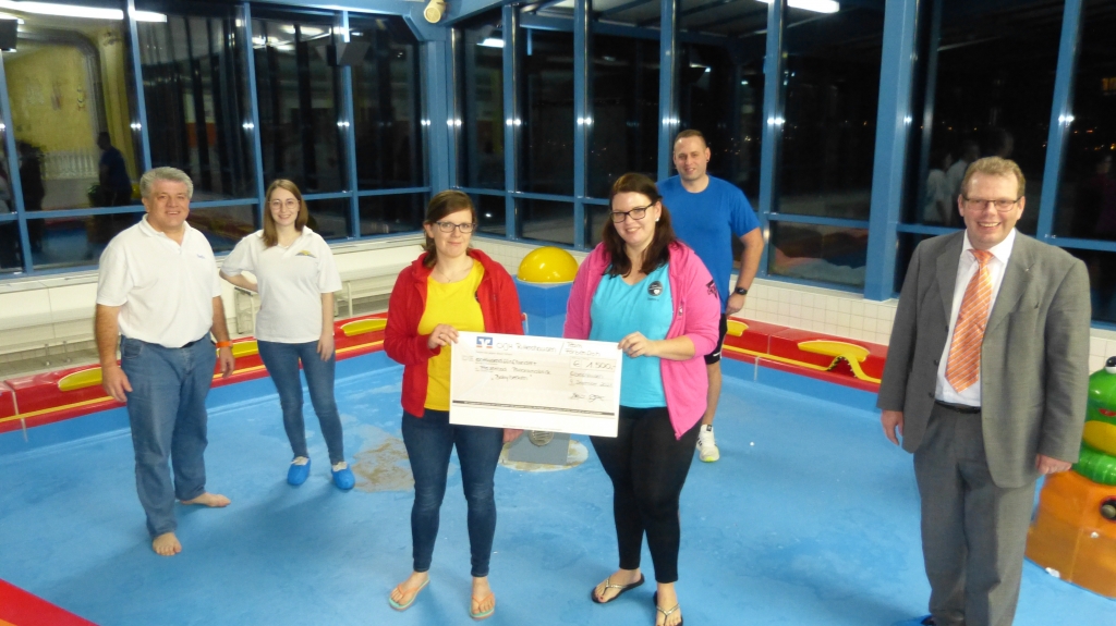 Spendenübergabe im alten Babybecken (von links): Stefan Nadler und Daniela Scheffel vom Förderverein freuen sich über den Erlös der Rittershäuser Kinderkleiderbörse, den Julia Ciliox und Sandra Becker überreichen. Roman Vomrath vom Freizeitbad und Bürgermeister Götz Konrad freuen sich über das Engagement der Eltern